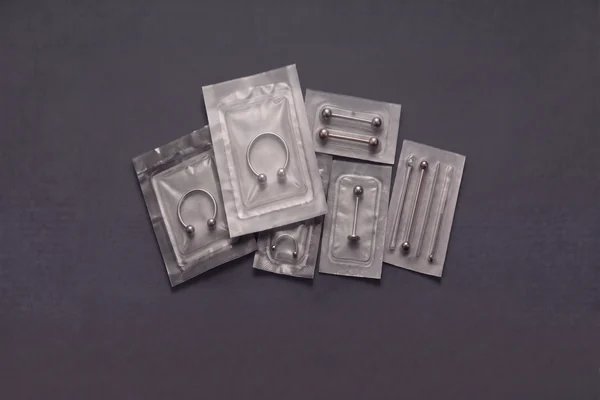 Sealed body jewellery pouches on a charcoal studio background