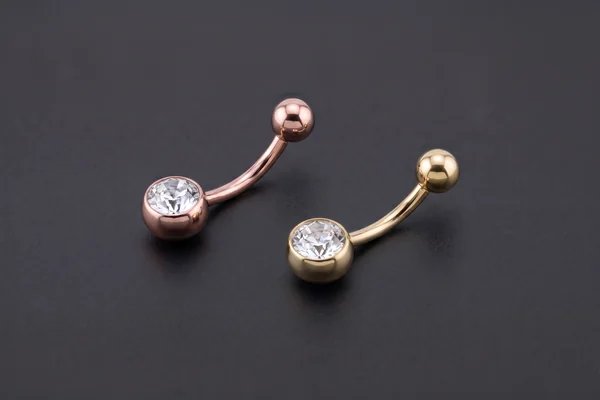 Rose-gold and gold curved belly bars with clear gemstones